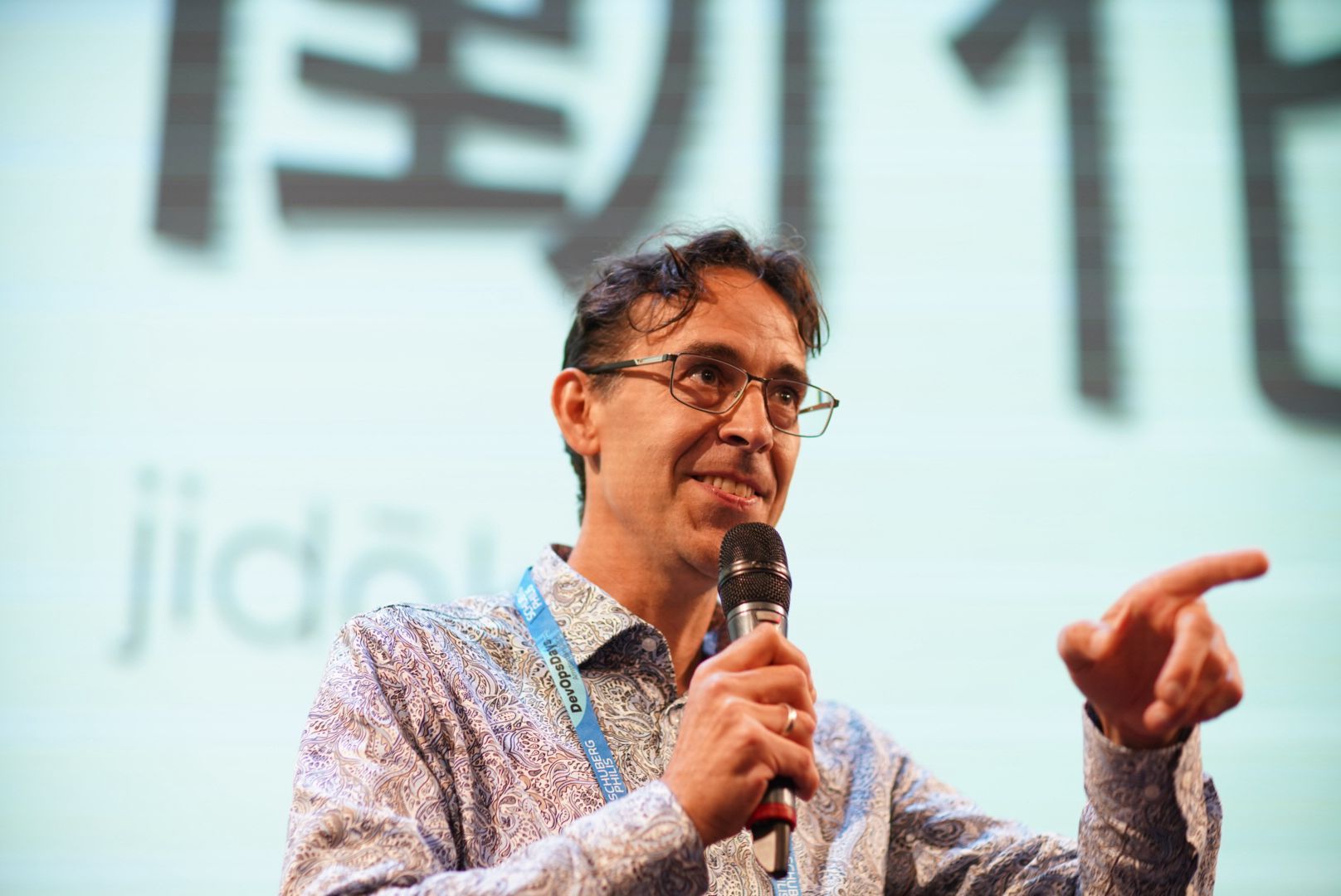 Picture of our colleague Robin at the stage of DevOps Days 2025 with a microfone in his hand.