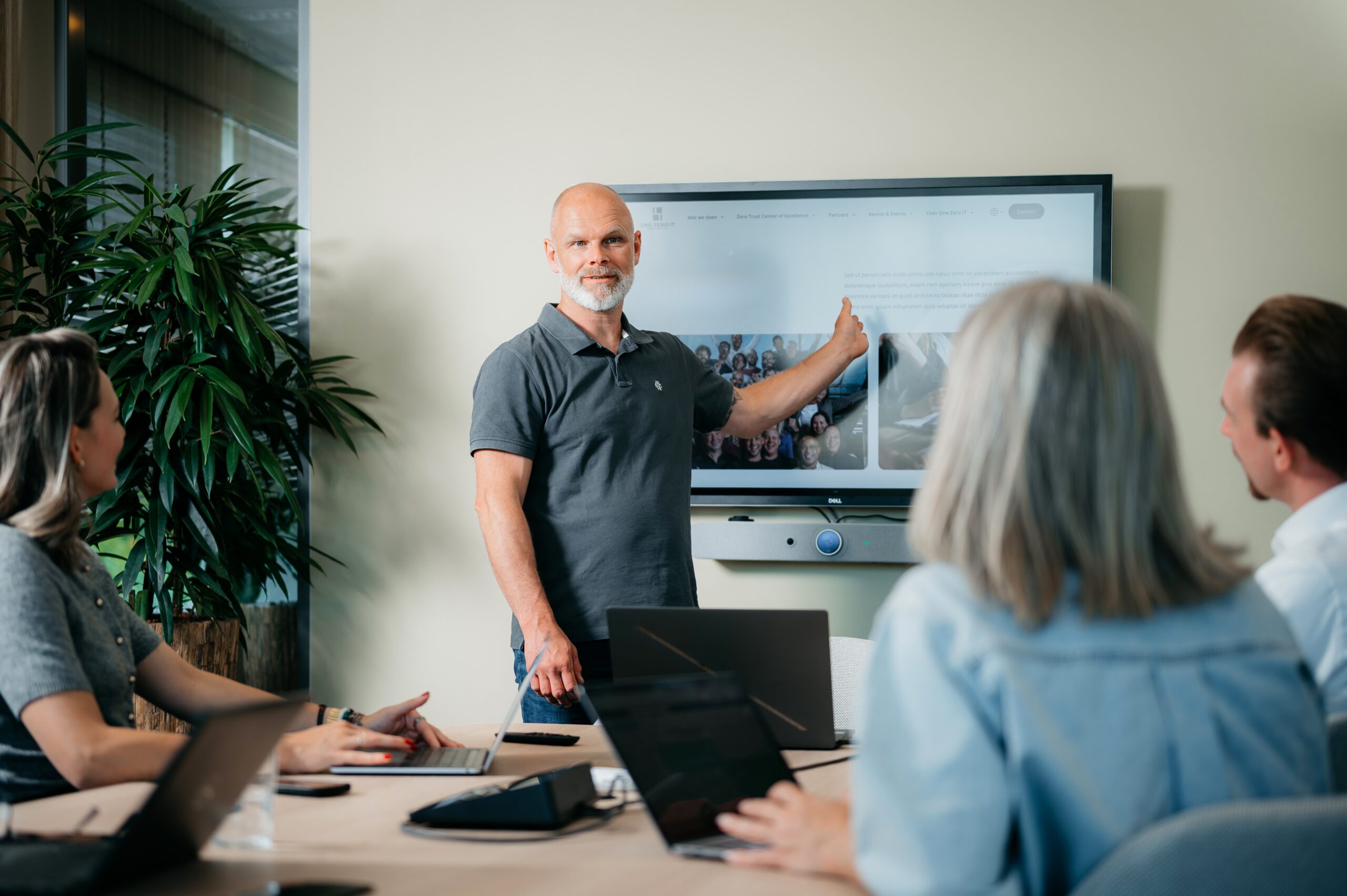 Man standing in front of a television screen presenting a Zero Trust project to fellow project members