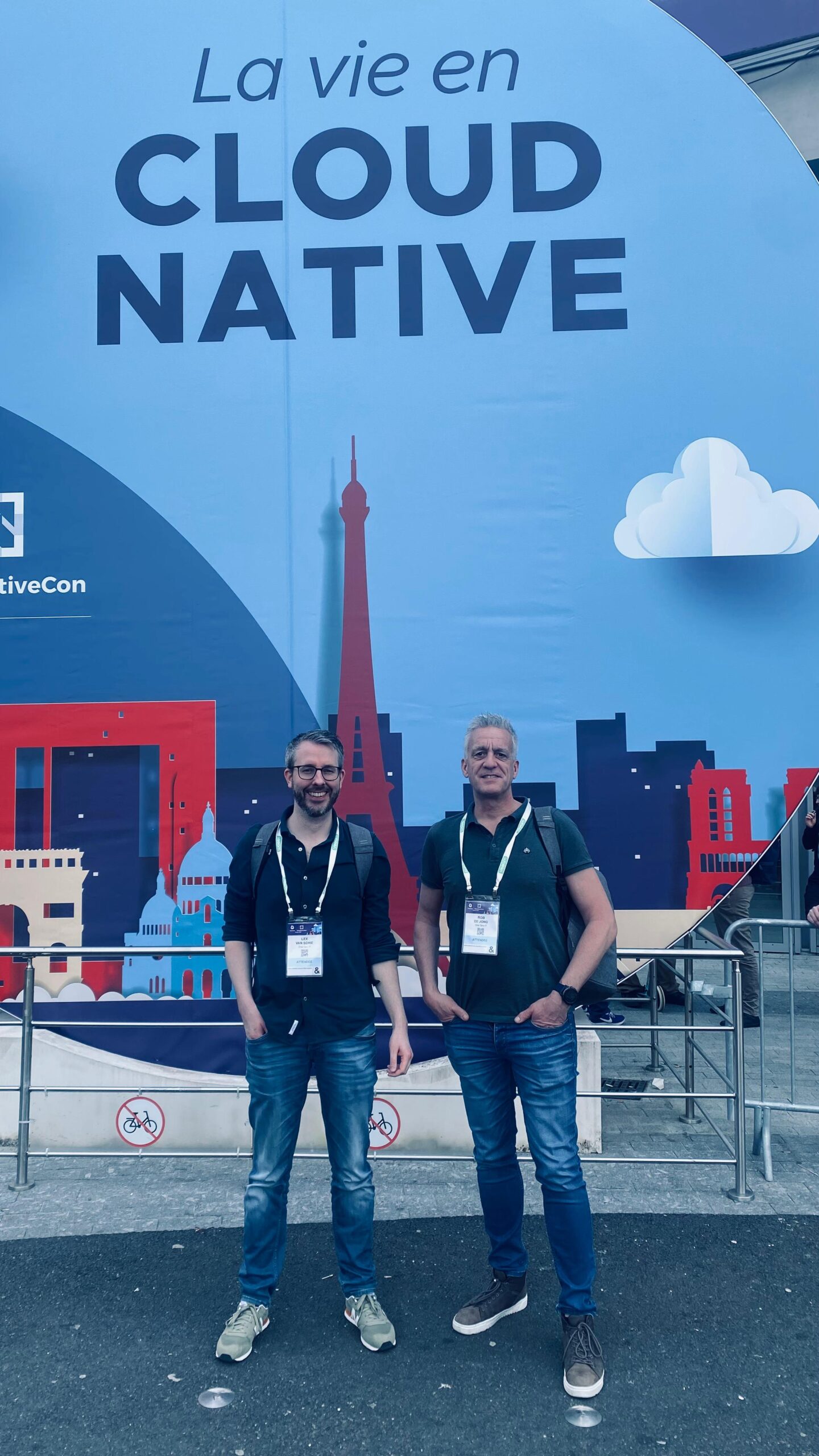 Two people standing in front of an exhibition hall during Cloud Native 2024