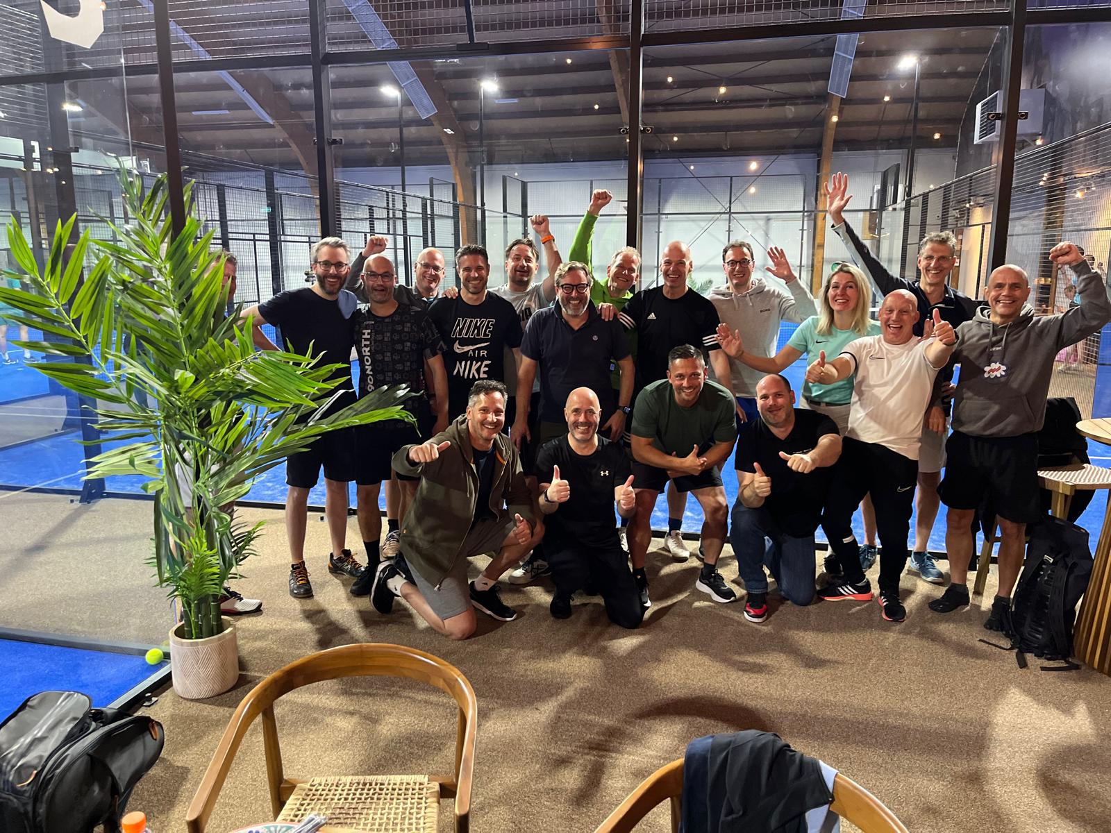 Group of people cheering and posing to celebrate a business padel event